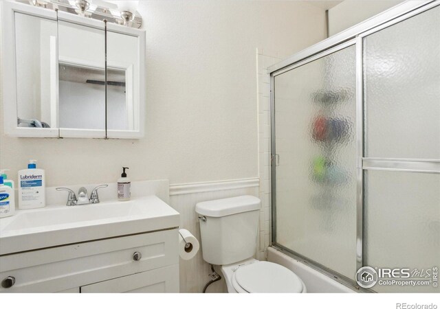 2315 Spruce St, Boulder, CO 80302 - full bath featuring toilet, vanity, a wainscoted wall, and bath / shower combo with glass door
