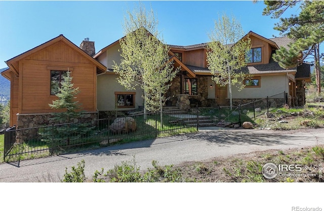 1049 Pine Knoll Dr, Estes Park, CO 80517 - view of front of property featuring stone siding, a fenced front yard, a chimney, and stucco siding