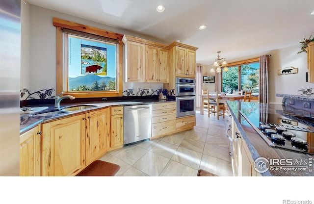 1049 Pine Knoll Dr, Estes Park, CO 80517 - kitchen with stainless steel appliances, light brown cabinetry, dark countertops, a chandelier, and a sink