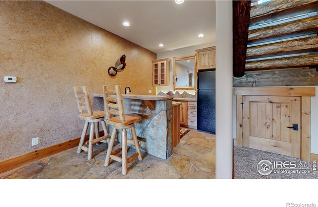 1049 Pine Knoll Dr, Estes Park, CO 80517 - kitchen with freestanding refrigerator, stone tile flooring, recessed lighting, a breakfast bar, and baseboards