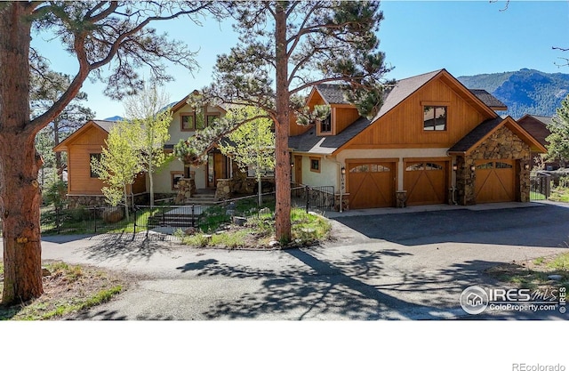 1049 Pine Knoll Dr, Estes Park, CO 80517 - view of front of home featuring stone siding, driveway, a fenced front yard, a mountain view, and an attached garage