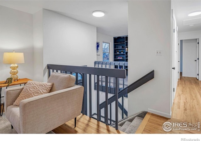 corridor featuring an upstairs landing, wood finished floors, and baseboards