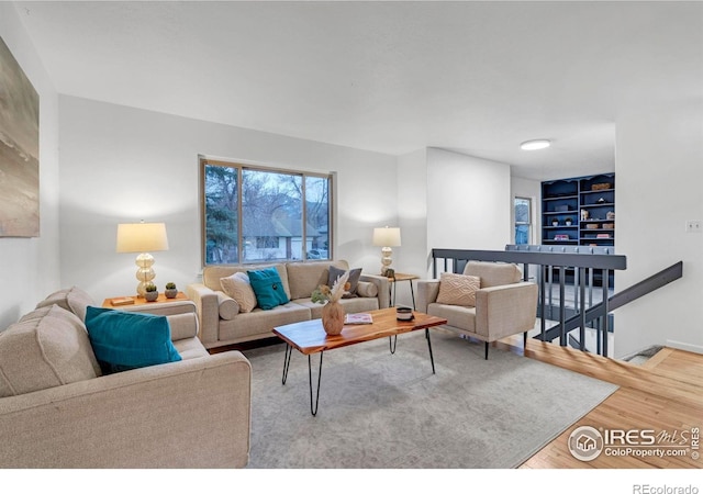 living area featuring wood finished floors and built in shelves