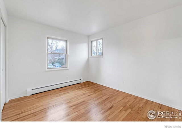 spare room featuring baseboard heating, wood finished floors, and baseboards
