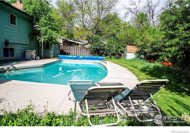 view of pool featuring fence and a shed