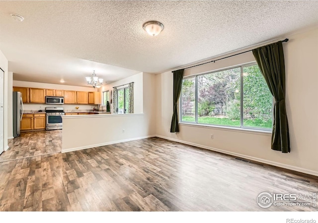 1842 Reliance Cir, Superior, CO 80027 - unfurnished living room featuring a chandelier, wood finished floors, plenty of natural light, a textured ceiling, and baseboards