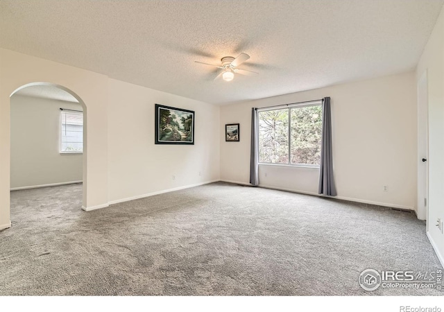 1842 Reliance Cir, Superior, CO 80027 - empty room with arched walkways, plenty of natural light, carpet, and a textured ceiling