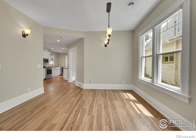 unfurnished dining area with light wood-style floors, baseboards, plenty of natural light, and recessed lighting