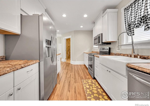 kitchen featuring stainless steel appliances, white cabinetry, light wood finished floors, recessed lighting, and baseboards