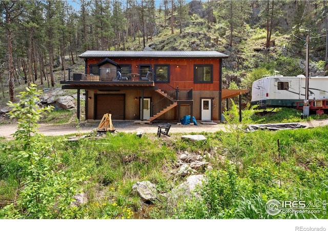200 Falls Creek Dr, Bellvue, CO 80512 - back of house featuring stairs, concrete driveway, a garage, a deck, and a view of trees