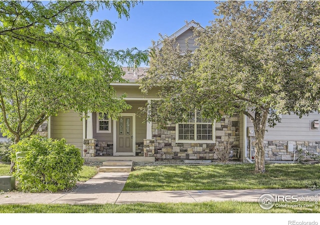 view of property hidden behind natural elements featuring stone siding, a front lawn, and a porch