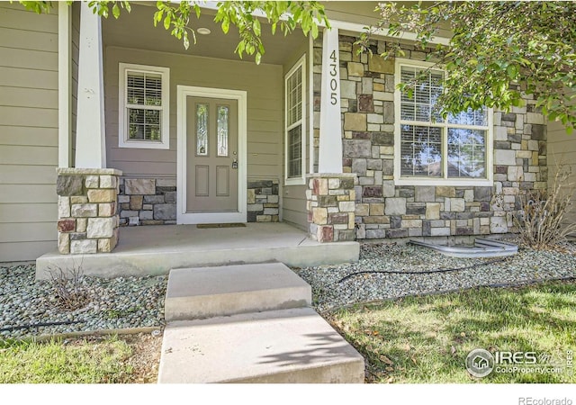 doorway to property with stone siding and covered porch