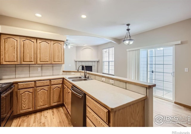 kitchen with a sink, stainless steel appliances, a peninsula, light wood-style flooring, and recessed lighting