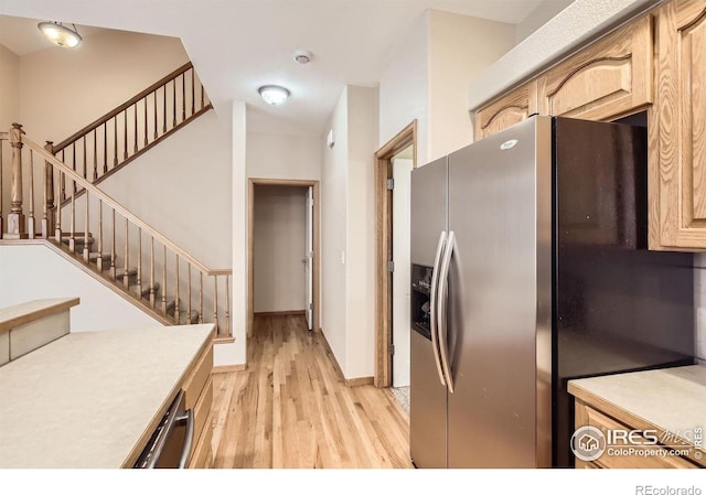 kitchen with appliances with stainless steel finishes, light wood-style flooring, light countertops, and baseboards