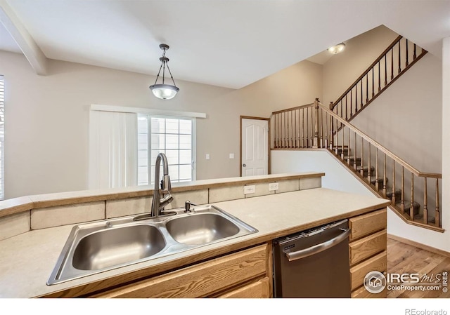 kitchen with dishwasher, a sink, light wood-style floors, light countertops, and hanging light fixtures