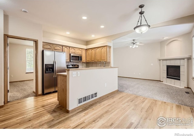kitchen featuring stainless steel appliances, a ceiling fan, baseboards, light wood finished floors, and recessed lighting