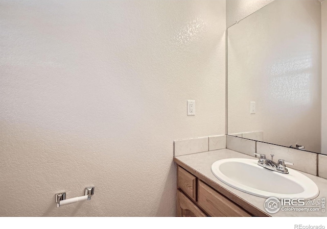 bathroom featuring vanity and a textured wall