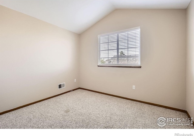 carpeted spare room with vaulted ceiling and baseboards