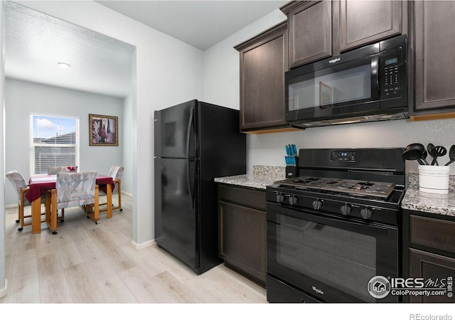 kitchen with black appliances, dark brown cabinetry, light wood-style flooring, light stone countertops, and baseboards