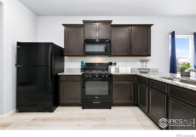 kitchen with black appliances, a sink, light stone counters, and dark brown cabinetry