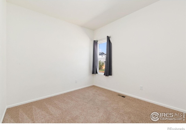 spare room featuring carpet and baseboards