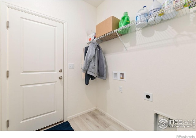 clothes washing area with light wood finished floors, hookup for a washing machine, electric dryer hookup, and baseboards