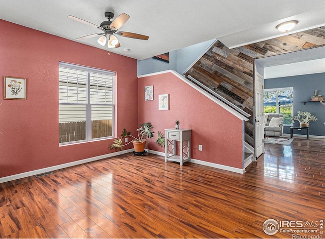 interior space with ceiling fan, wood finished floors, baseboards, and stairway