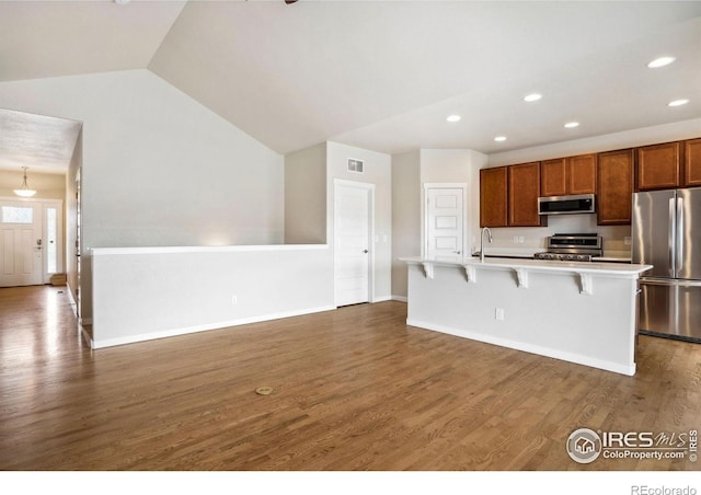 1468 Moraine Valley Dr, Severance, CO 80550 - kitchen with appliances with stainless steel finishes, light countertops, a breakfast bar area, dark wood-style floors, and recessed lighting