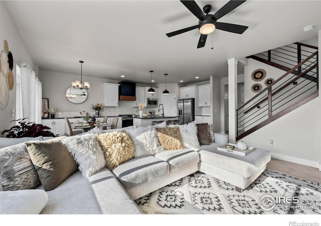 living area featuring a chandelier, ceiling fan, wood finished floors, stairs, and recessed lighting