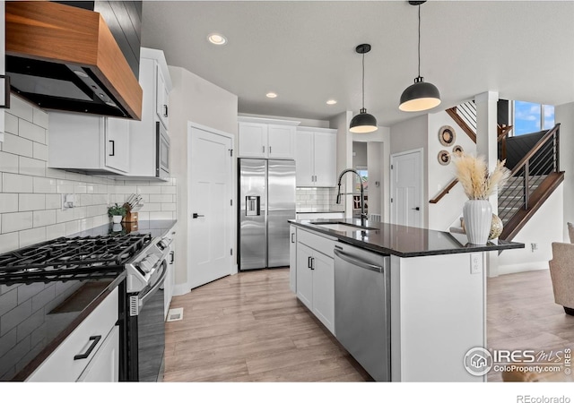 kitchen with a sink, appliances with stainless steel finishes, premium range hood, light wood finished floors, and recessed lighting