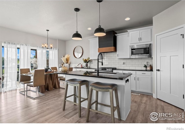 kitchen with stainless steel microwave, dark countertops, decorative backsplash, light wood-style flooring, and recessed lighting