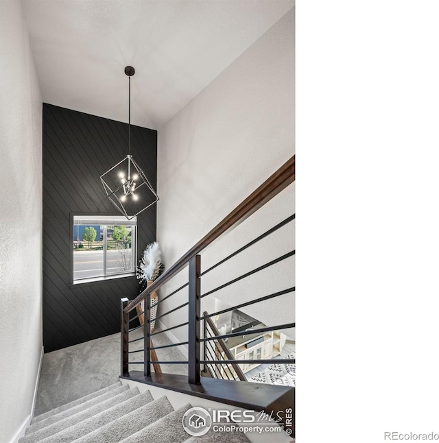 stairway featuring a high ceiling, a chandelier, and carpet