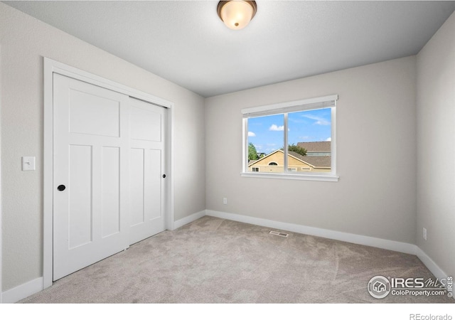 unfurnished bedroom with carpet, baseboards, and a closet
