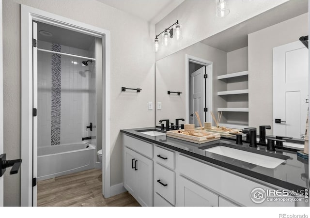 full bathroom with wood finished floors, toilet, double vanity, bathing tub / shower combination, and baseboards