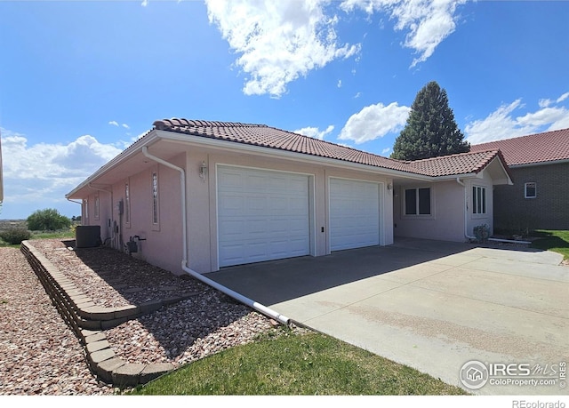 107 Fairway Ln, Fort Morgan, CO 80701 - view of home's exterior with a tiled roof, stucco siding, a garage, driveway, and cooling unit