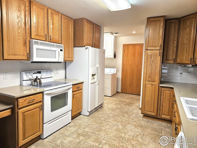 107 Fairway Ln, Fort Morgan, CO 80701 - kitchen with white appliances, washer / clothes dryer, tasteful backsplash, a sink, and light countertops