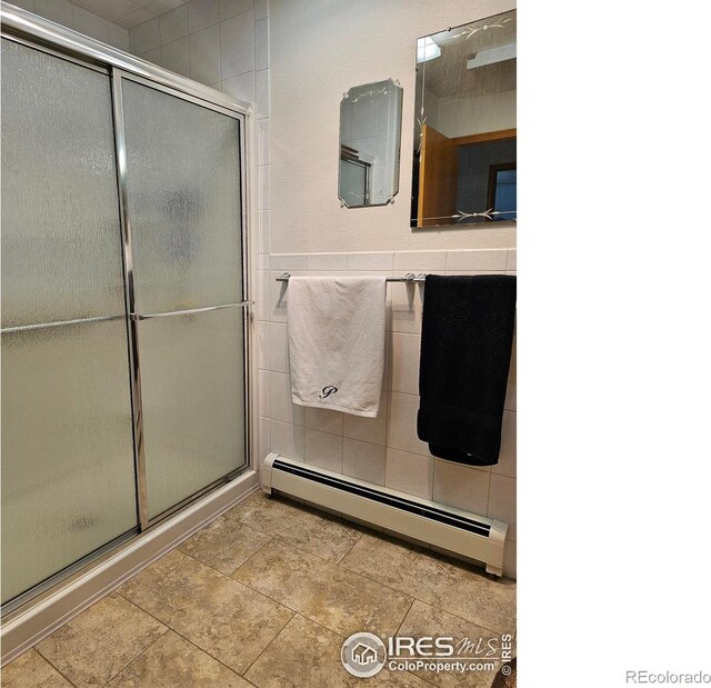 107 Fairway Ln, Fort Morgan, CO 80701 - full bathroom featuring baseboard heating, an enclosed shower, and tile walls
