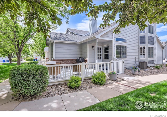 39 Sebring Ln, Johnstown, CO 80534 - view of front of property featuring a chimney, central AC unit, brick siding, and a wooden deck