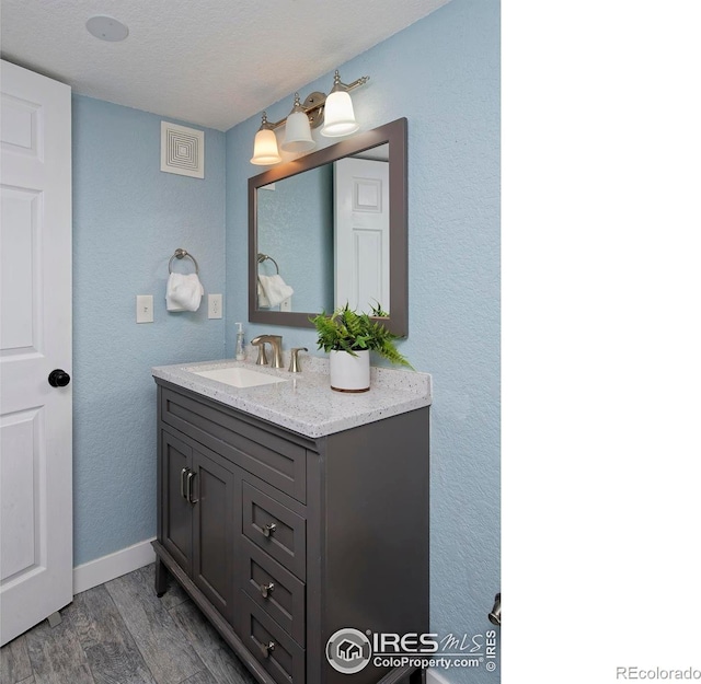 bathroom with wood finished floors, vanity, and baseboards
