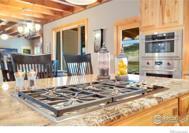 6950 W County Road 18, Loveland, CO 80537 - kitchen featuring stainless steel appliances, a chandelier, light stone counters, light brown cabinets, and hanging light fixtures