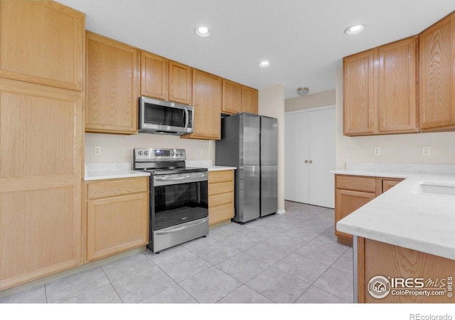 1724 Holeman Dr, Erie, CO 80516 - kitchen with appliances with stainless steel finishes, light countertops, recessed lighting, light tile patterned floors, and light brown cabinets