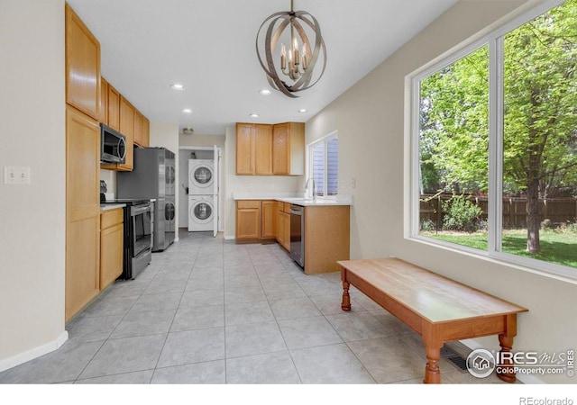 1724 Holeman Dr, Erie, CO 80516 - kitchen with stacked washer / dryer, stainless steel appliances, a chandelier, light countertops, and baseboards