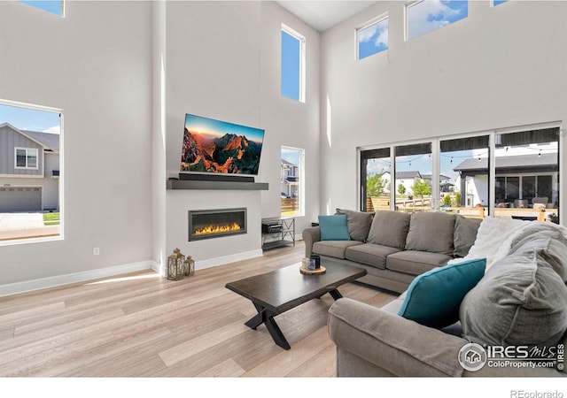 5085 Blanchette St, Timnath, CO 80547 - living area with wood finished floors, a glass covered fireplace, a towering ceiling, and baseboards