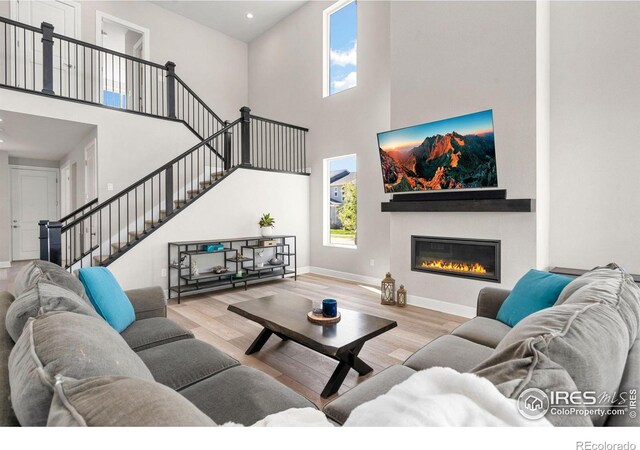 5085 Blanchette St, Timnath, CO 80547 - living room with a towering ceiling, wood finished floors, stairway, healthy amount of natural light, and a glass covered fireplace