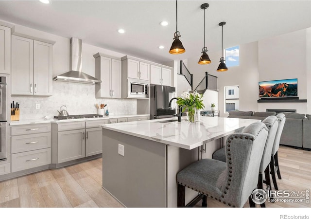 5085 Blanchette St, Timnath, CO 80547 - kitchen featuring wall chimney range hood, appliances with stainless steel finishes, a sink, light wood finished floors, and recessed lighting
