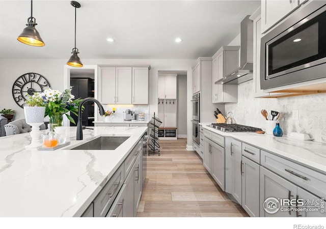 5085 Blanchette St, Timnath, CO 80547 - kitchen with a sink, stainless steel appliances, wall chimney range hood, tasteful backsplash, and hanging light fixtures
