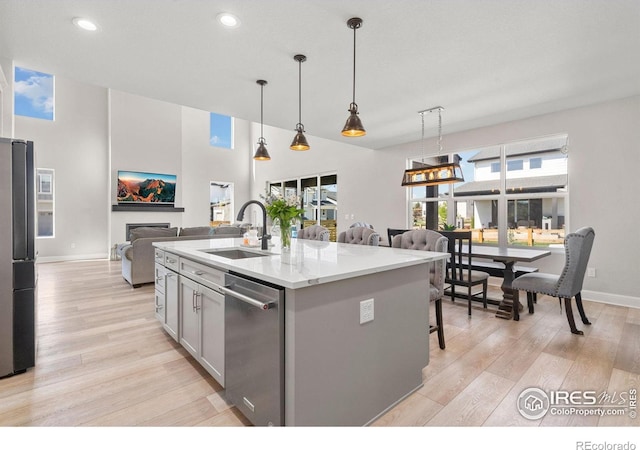 5085 Blanchette St, Timnath, CO 80547 - kitchen featuring a sink, dishwasher, open floor plan, light wood-style floors, and baseboards
