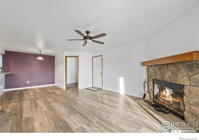 7820 W 87th Dr Unit K, Arvada, CO 80005 - unfurnished living room with a stone fireplace, a ceiling fan, wood finished floors, and baseboards