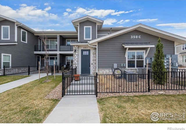 350 High Point Dr Unit 201, Longmont, CO 80504 - view of property featuring a gate, a balcony, stone siding, and central AC unit