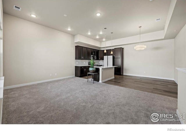 350 High Point Dr Unit 201, Longmont, CO 80504 - kitchen with open floor plan, freestanding refrigerator, dark carpet, light countertops, and an island with sink